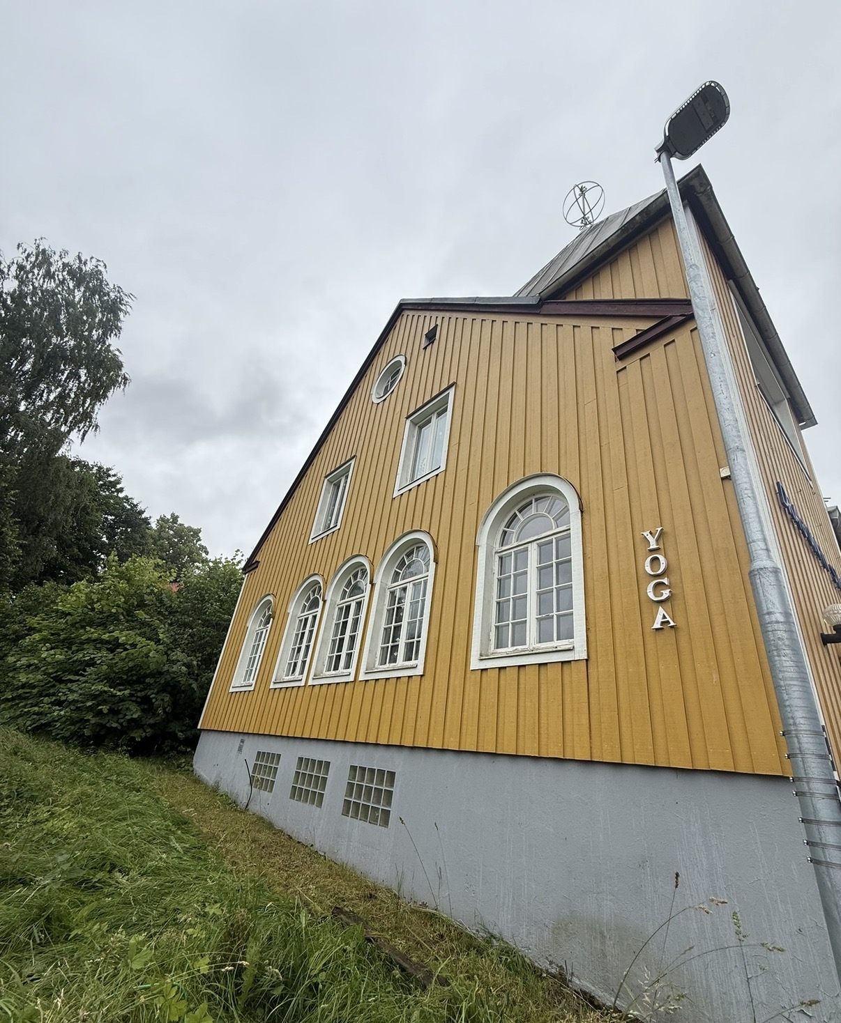 Gul träfasad med locklistpanel före fasadtvätt – smutsränder, alger och spindelnät under takfoten